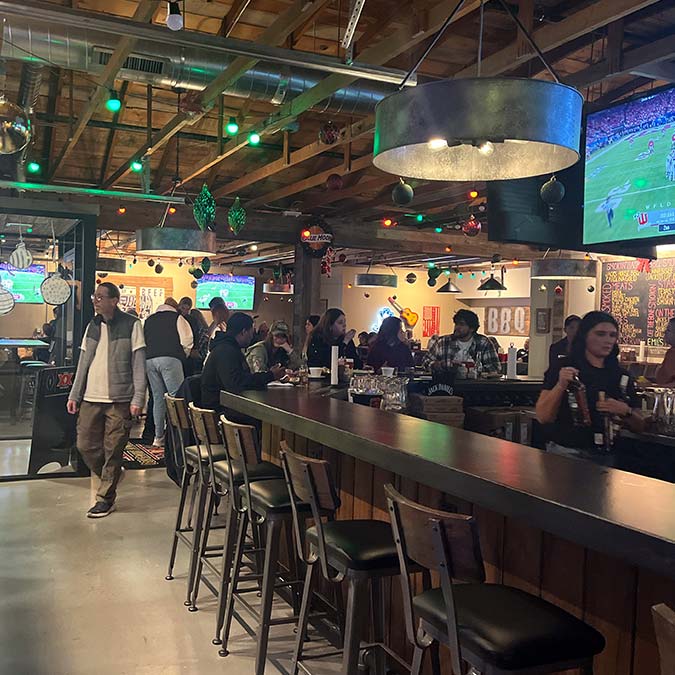 Bar with people socializing, bartenders serving drinks at a BBQ restaurant in Mundelein IL.