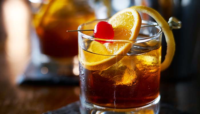 A cocktail with ice, orange slices, and a cherry garnish—perfect for a Sports Bar in Mundelein IL.