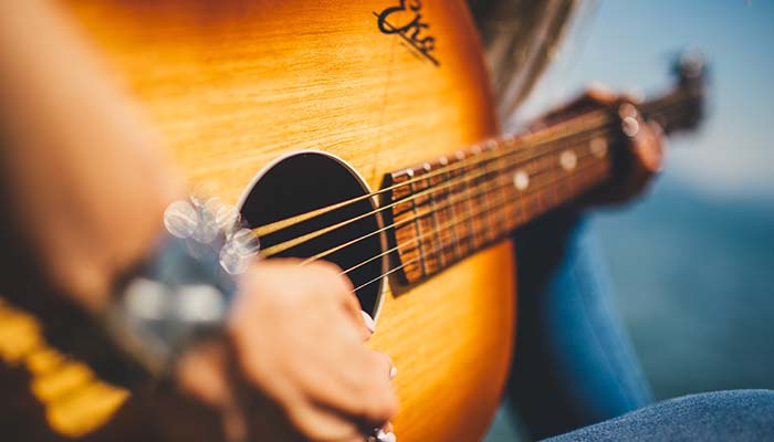 Close-up of Jimmy Carol’s hand strumming an acoustic guitar at Live Music Mundelein.