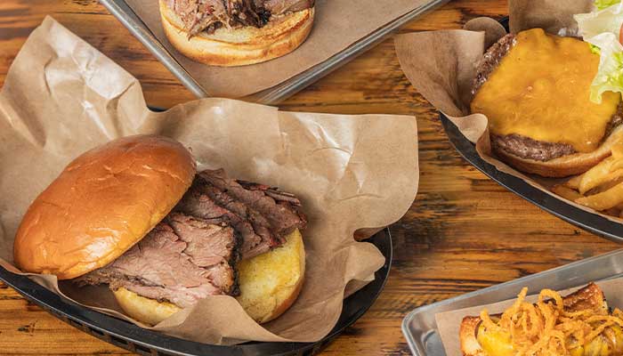 BBQ Menu in Mundelein IL: Brisket sandwich, cheeseburger with fries, and fried onions tray.