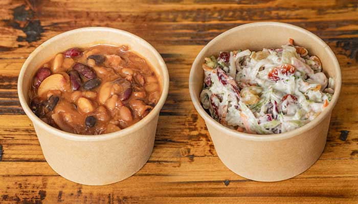Two brown paper bowls of beans from a BBQ Menu in Mundelein IL sit on a wood table.